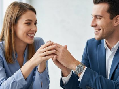オフィスで微笑み合う男女の手元クローズアップ