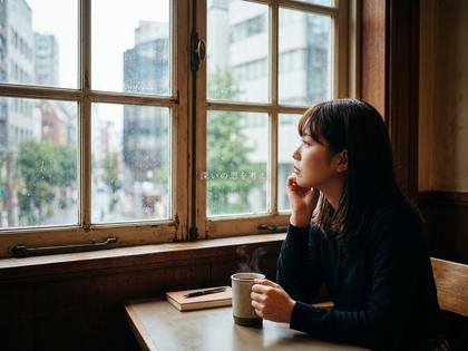 窓際でコーヒーを持ち物思いにふける女性
