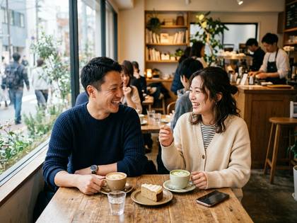カフェで笑顔の男女が向かい合い、コーヒーとケーキを楽しむ。