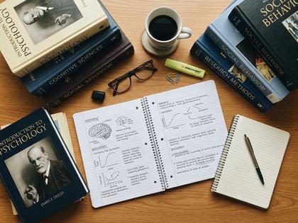 心理学の本とノートが置かれたデスクの俯瞰イメージ