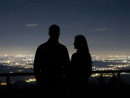 夜景が見える展望スポットで並んで立つカップルのシルエット