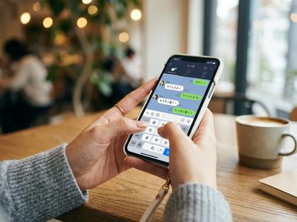 スマホでLINEのやり取りをしている女性の手元のクローズアップ