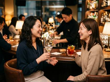 バーカウンターで笑顔でカクテルを楽しむ二人の女性。