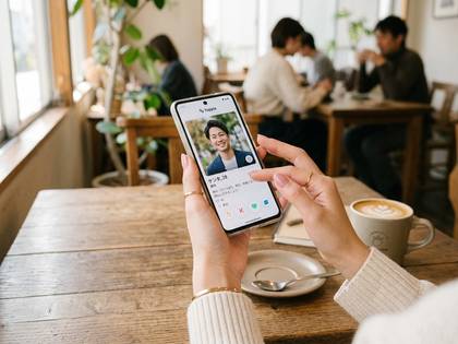 カフェで女性がスマホで出会い系アプリの男性プロフィールを見る
