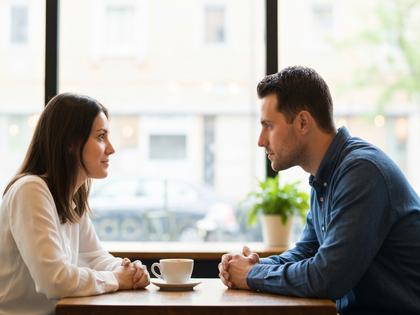 カフェで向かい合って会話するカップル、ふんわりとした自然光