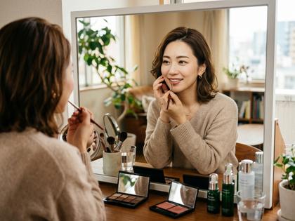 鏡の前でメイクを整える30代女性のイメージ、800px × 600px