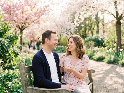 春の公園で楽しそうに会話する男女、自然光あふれる柔らかい雰囲気