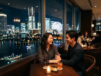 窓際で横浜の夜景を楽しみながら笑顔で話すカップル。