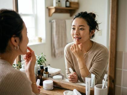 鏡の前でリップを塗る女性。