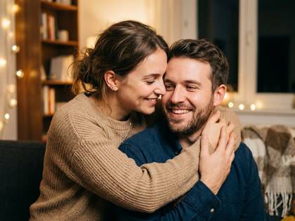 温かい部屋で笑顔で抱き合う男女のカップル。