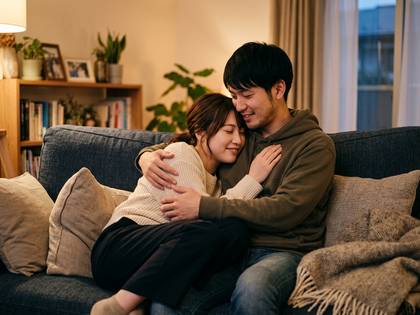 ソファで寄り添い、安らぐ笑顔のカップル。