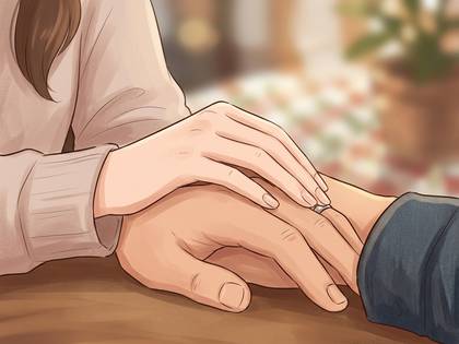 男女がテーブルの上で手を重ね、男性の薬指に指輪。