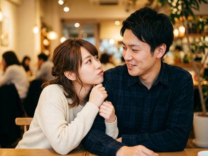 カフェで甘える女性と優しく微笑む男性カップル。