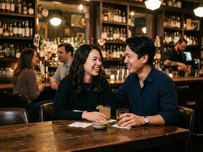 バーで笑顔の男女が飲み物を片手に談笑している。