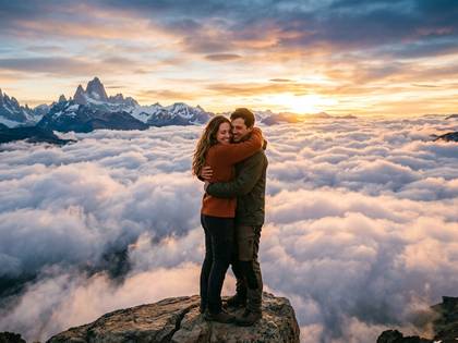 夕焼け空の下、山頂の雲海で抱き合うカップル。