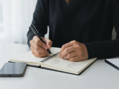 アプリの比較表をノートに書き込む女性の手元