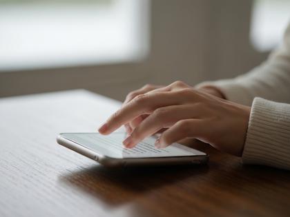 スマホ画面にメッセージを打ち込んでいる女性の手元のクローズアップ