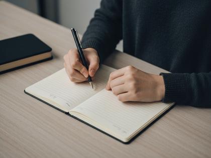 ノートに恋愛のメモを書く女性の手元