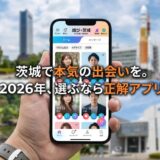 茨城の風景を背景に、マッチングアプリ「結び・茨城」のスマホ画面を持つ手元。