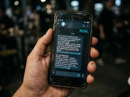 手が持つスマホ画面に、URLを含む不審なメッセージが表示されている。