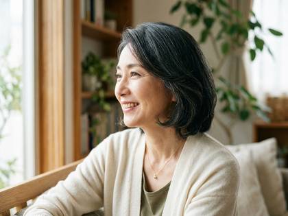 窓辺で幸せそうに微笑む中年の女性。