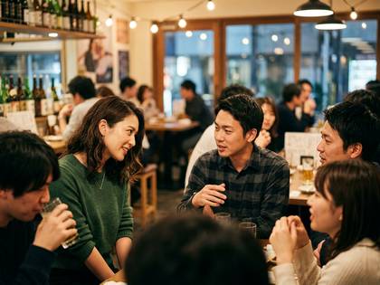 活気ある居酒屋で、楽しそうに談笑する友人たち。手前の男女が笑顔。