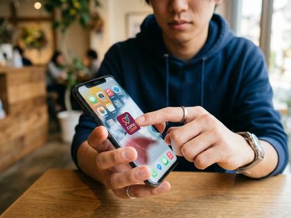 スマホ画面でマッチングアプリを選んでいる20代男性の手元のイメージ