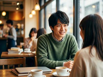 カフェの窓際で笑顔で向かい合い、会話するアジア人男女。