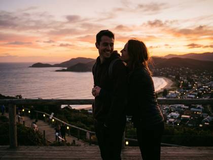 夕焼けの海岸で寄り添う笑顔のカップル。
