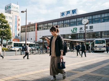 茨城県の水戸駅前でスマホを見ながら歩く若い女性のイメージ写真