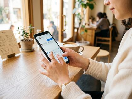 スマホでメッセージを打つ女性の手元、明るい雰囲気