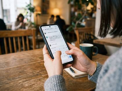 カフェでスマホを操作し、チャット画面を見る女性。