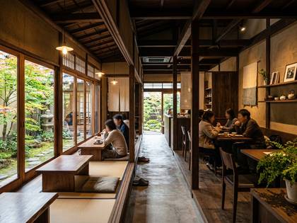 窓から日本庭園が見える和風カフェ。人々が食事や会話を楽しんでいる。