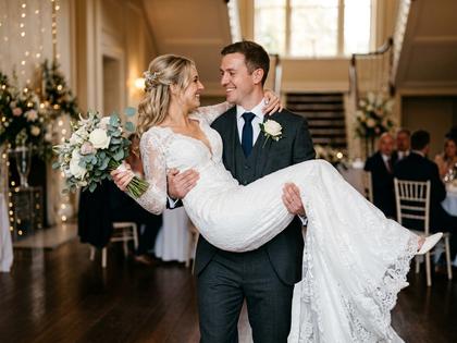 結婚式でウェディングドレスの新婦を新郎がお姫様抱っこしている幸せそうな写真