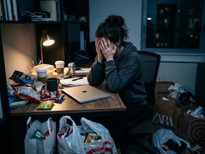夜のデスクでノートパソコンを閉じ、深呼吸している20代女性の横顔