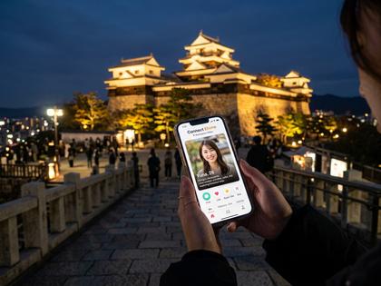 松山城を背景にスマホでマッチングアプリを操作している女性のイメージ