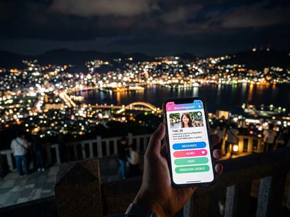 長崎の稲佐山から見える夜景とスマートフォンを持つ女性のイメージ