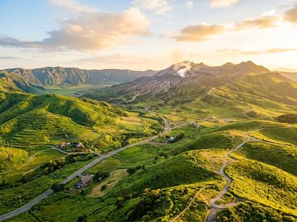 阿蘇の風景を背景にした自然な笑顔の女性の写真イメージ