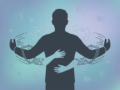ソファに並んで座るカップルが後ろから抱き合いながらスマホを一緒に見ている様子