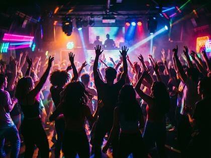 夜のクラブで音楽に合わせて手を上げて盛り上がる若者たちのシルエット 800x600