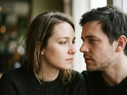 ソファに並んで座り、キスの後に照れて目を合わせる若いカップル、800×600